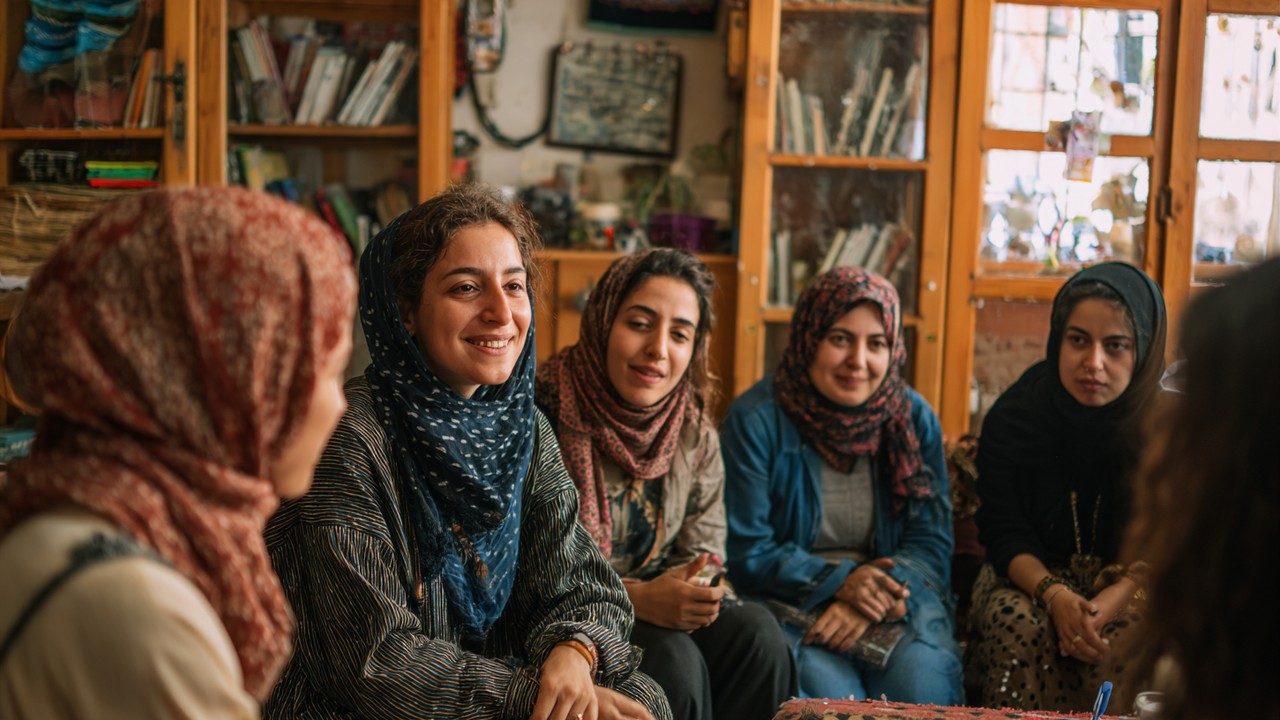 Diverse group of Turkish women engaged in a lively finance workshop in a cozy community space, promoting support and empowerment.